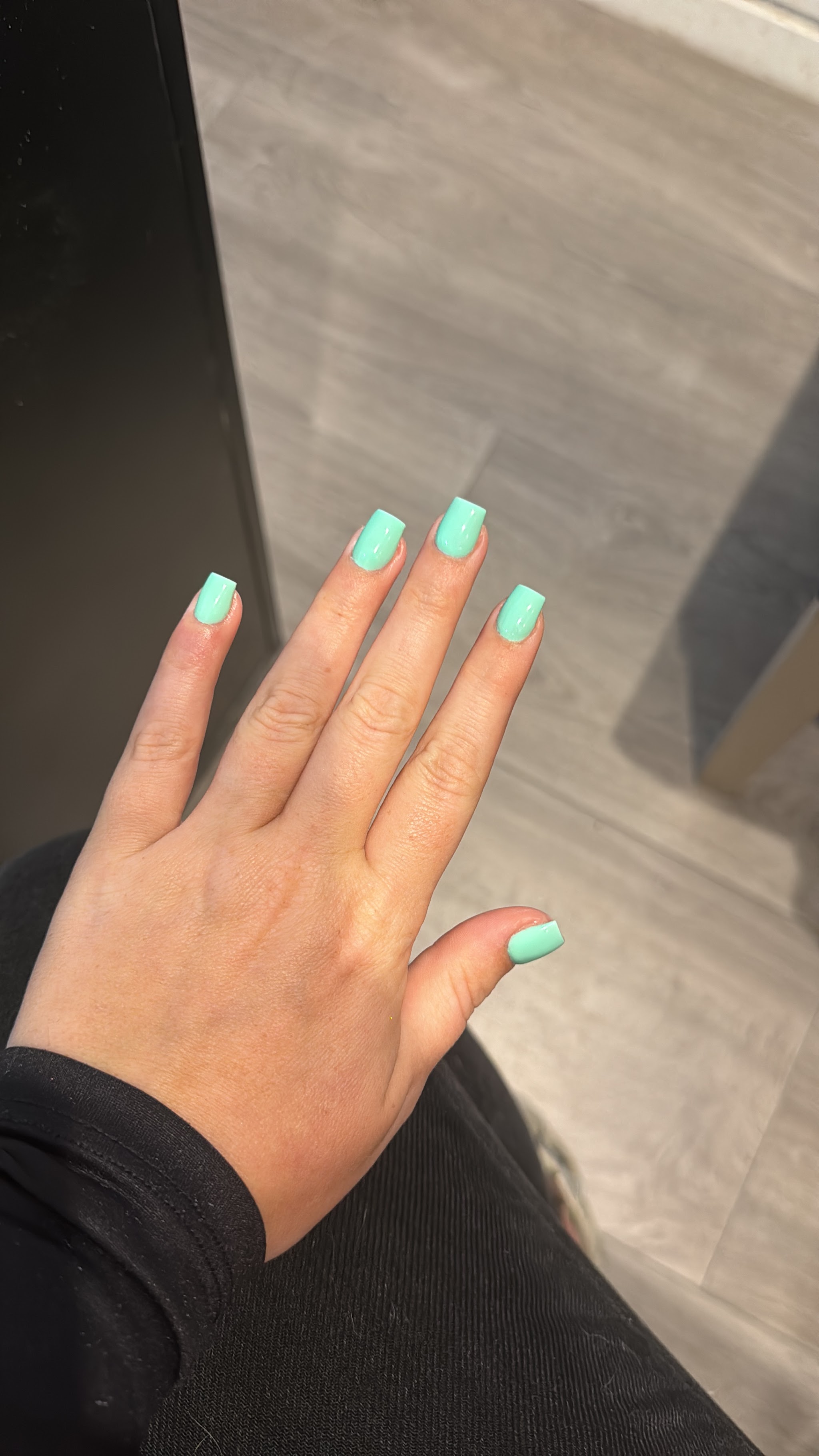 Korte mintgroene set op een hand tegen een grijze muur